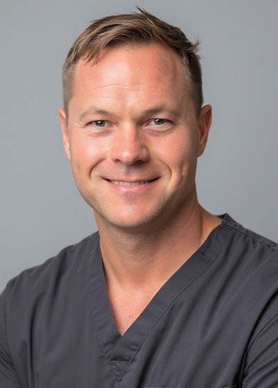A man wearing a black shirt and headphones stands in front of a group of people. Description generated by AI