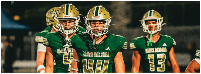 Three people wearing green football uniforms and helmets with “Santa Barbara" written on the jerseys stand on a field at night. Description generated by AI