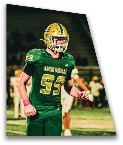 A person wearing a green sports uniform with the number 93 is standing on a football field with other players in the background. Description generated by AI