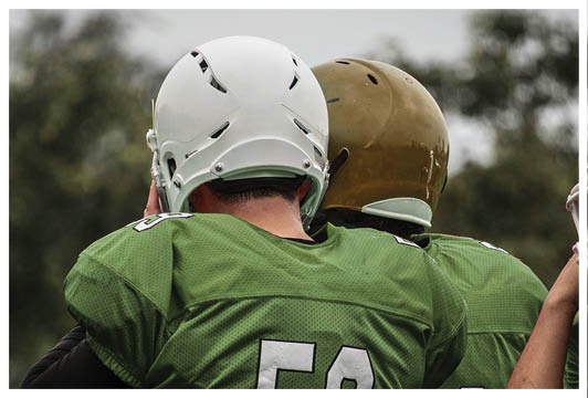 Two men wearing green jerseys. Description generated by AI