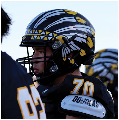 A group of football players huddled together on the field. Description generated by AI