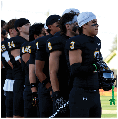 A group of football players huddled together on the field. Description generated by AI
