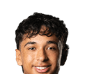 Person with curly hair and light eyes looking forward against a white background. Description generated by AI