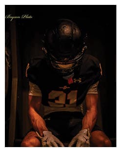 Two football players wearing black jerseys and holding hands. Description generated by AI