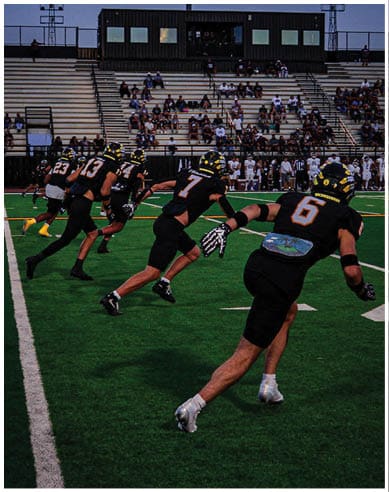 A group of football players huddled together on the field. Description generated by AI