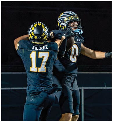 A group of football players huddled together on the field. Description generated by AI