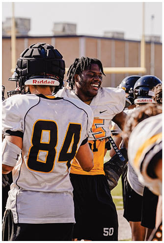 A person wearing a red and white Gainesville football jersey with the number 29 is standing with another person in a similar uniform visible in the background. Description generated by AI