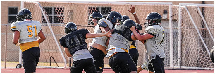 Two adults smiling and standing close together outdoors with buildings and a parking structure in the background. Description generated by AI
