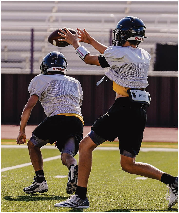 A person in a red football uniform with the word Gainesville and the number one stands with an arm around another person wearing a black outfit, both smiling outdoors. Description generated by AI
