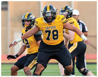 People in yellow and black football uniforms are on a field with one player in a white and purple uniform facing them. Description generated by AI