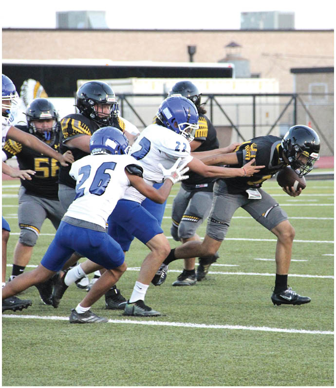 Two people in football uniforms are engaged in a blocking action on a football field during a game. Description generated by AI
