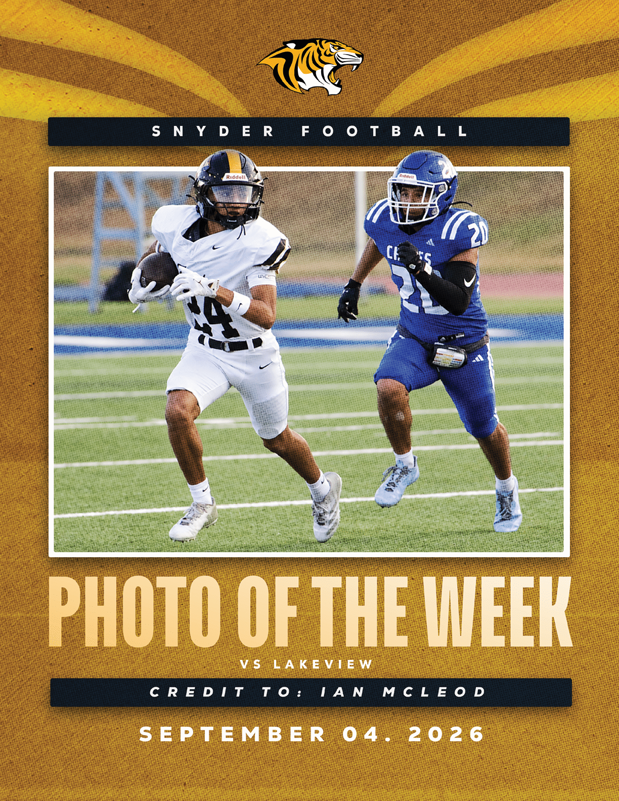 Two people in football uniforms are actively running on a field during a game, with one holding the ball and the other pursuing. Description generated by AI
