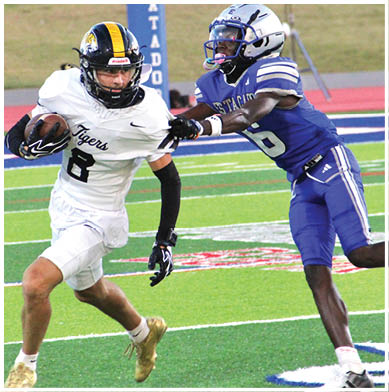 Two people wearing sports uniforms and gloves are engaged in a physical struggle on a football field. Description generated by AI