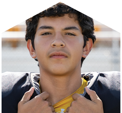 Person with short curly hair wearing a sports jersey and shoulder pads is adjusting their collar while looking directly at the camera. Description generated by AI