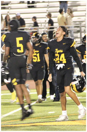 People in black and yellow football uniforms are on a field, with one person laughing and others standing nearby. Description generated by AI