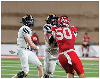 Two people in red football uniforms are engaging with two people in white football uniforms on a green field inside a stadium. Description generated by AI