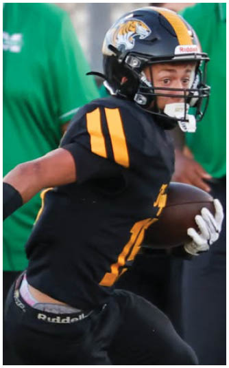 A person wearing a white and green sports uniform is in a bent forward position, likely participating in an athletic activity. Description generated by AI