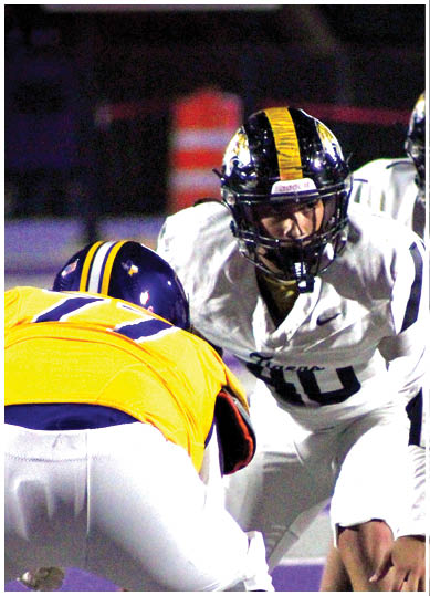 Two people in football uniforms and helmets are positioned facing each other on a field, appearing ready for a play. Description generated by AI