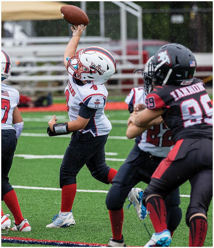 Three football players in blue and white uniforms running on a field. Description generated by AI