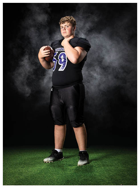Two football players wearing black jerseys and holding hands. Description generated by AI