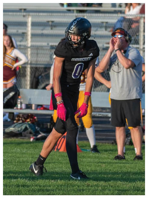 Two football players wearing black jerseys and holding hands. Description generated by AI