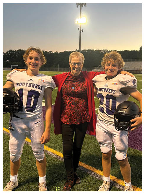 Two football players wearing black jerseys and holding hands. Description generated by AI