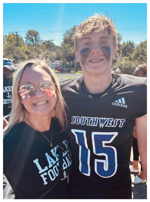 Two football players wearing black jerseys and holding hands. Description generated by AI