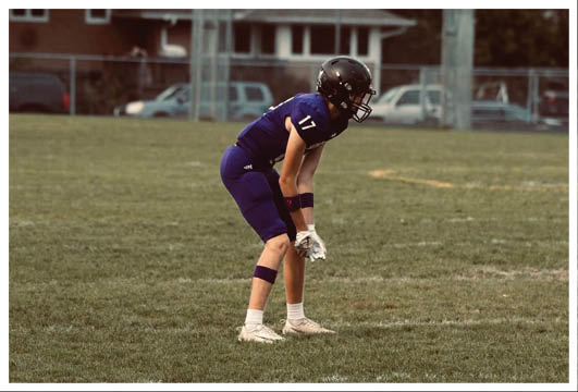 A football player wearing a blue and red jersey. Description generated by AI