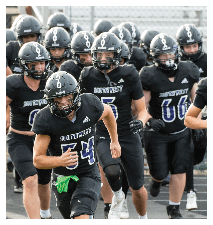 A football game is in progress with players on the field. One player is throwing a football while another player is trying to catch it. The players are wearing uniforms and are actively engaged in the game. AI generated content