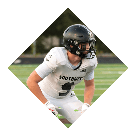 A football player wearing a black jersey with the number 10 sits on the ground with a football helmet on the ground next to him. AI generated content
