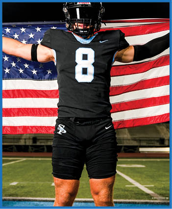 A football player stands on a field holding an American flag. AI generated content