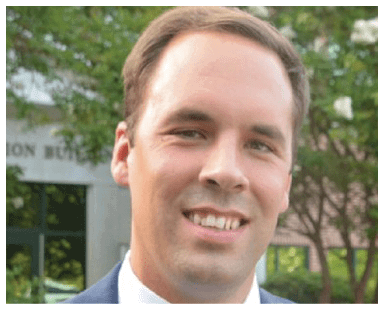 A man wearing a blue tie and a suit is smiling for the camera. AI generated content