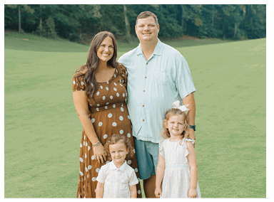A man, woman, and two children pose for a picture on a grassy field. AI generated content