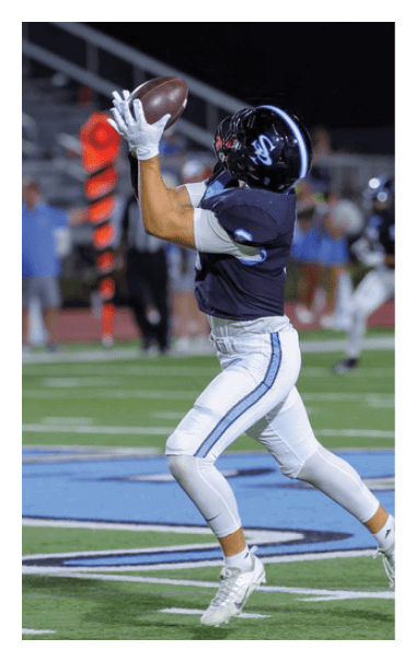 A football player in a black jersey catches a football on the field. AI generated content