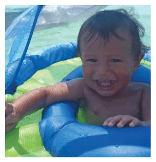 A young child is sitting in a blue and yellow inflatable ring, smiling and enjoying the water. AI generated content