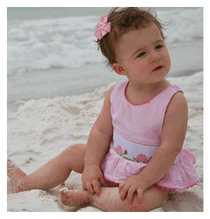 A young girl is sitting on the beach, wearing a pink dress and a bow in her hair. AI generated content