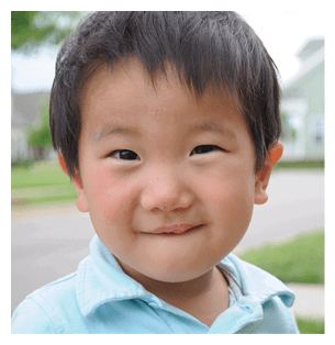 A young boy with a blue shirt and white collar is standing on the sidewalk. AI generated content
