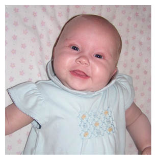 A baby wearing a blue dress is smiling and laying on a pink blanket. AI generated content