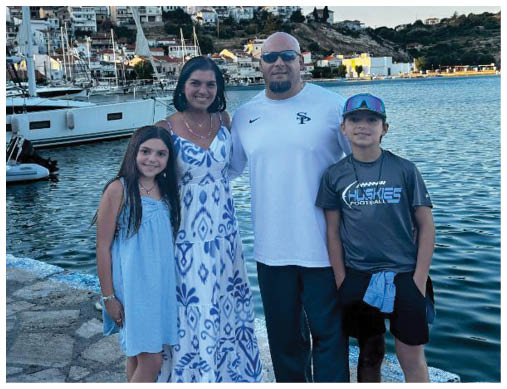 A man, woman, and two children pose for a photo in front of a body of water. AI generated content