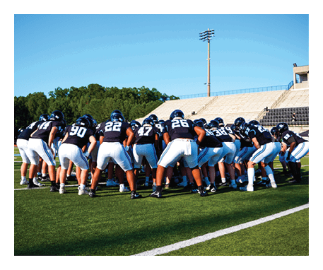 A group of football players huddled together on the field. AI generated content