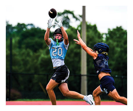 Two female athletes are playing a game of football. One player is trying to catch the ball while the other player is trying to block her. AI generated content