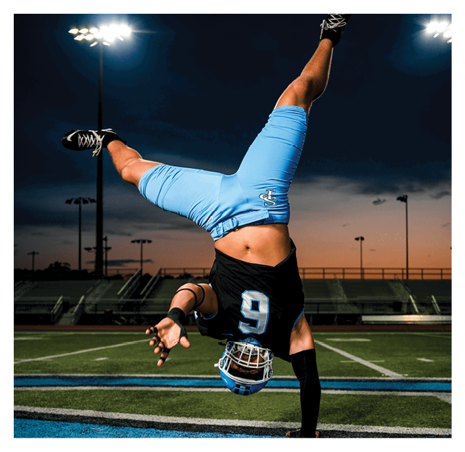 A man in a blue and black uniform is doing a handstand on a football field. AI generated content