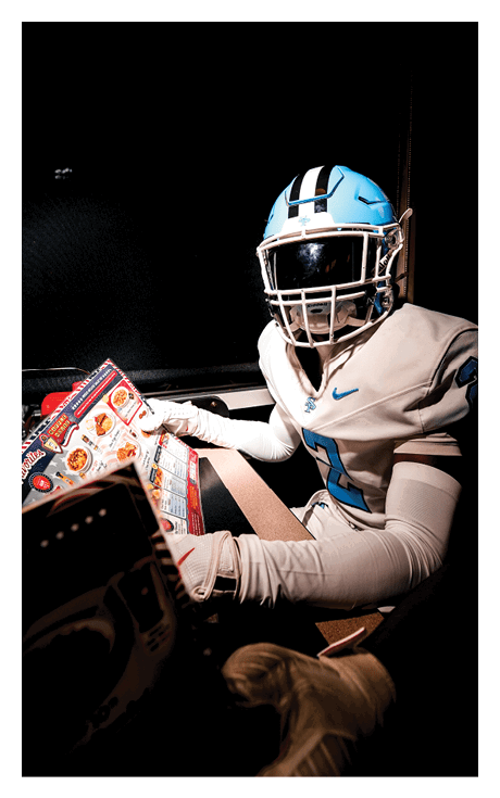 A football player wearing a helmet and a white jersey is sitting in a car. AI generated content