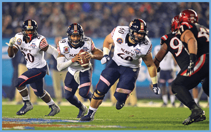 Two football players from opposing teams are running on the field. One player is holding a football and the other is wearing a pink jersey. AI generated content
