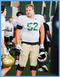 A football player wearing a white jersey with the number 52 on it stands on the field. AI generated content
