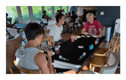 A group of people are gathered around a table playing a card game. AI generated content
