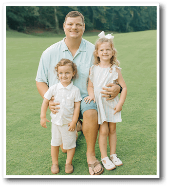 A man and two children pose for a picture on a grassy field. AI generated content
