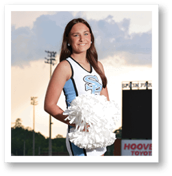 A cheerleader in a blue and white uniform stands on a football field holding a white pom pom. AI generated content