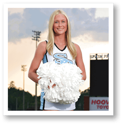 A cheerleader in a blue and white uniform stands on a football field holding a large white pom pom. AI generated content