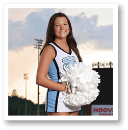 A cheerleader in a blue and white uniform stands on a football field holding a pom pom. AI generated content